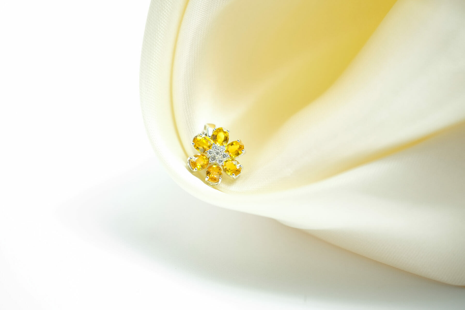 บุษราคัม (Yellow Sapphire) รูปดอกไม้บนผ้าไหมสีเหลือง